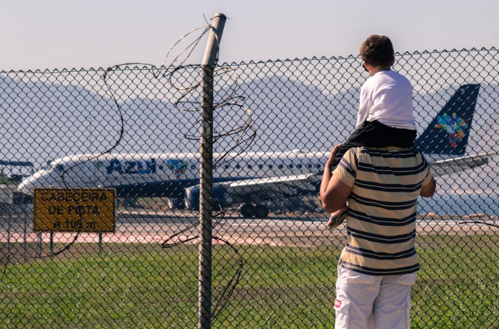 Pai carregando o filho de frente para um avião branco antes do embarque