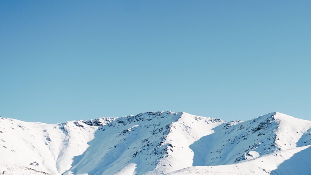 Montanha coberta de neve sob céu azul, representando um destino de inverno menos óbvio