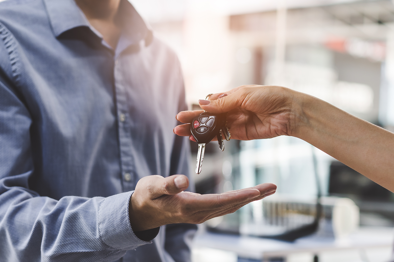 Vendedor entregando chave de carro para cliente em uma concessionária ou locadora