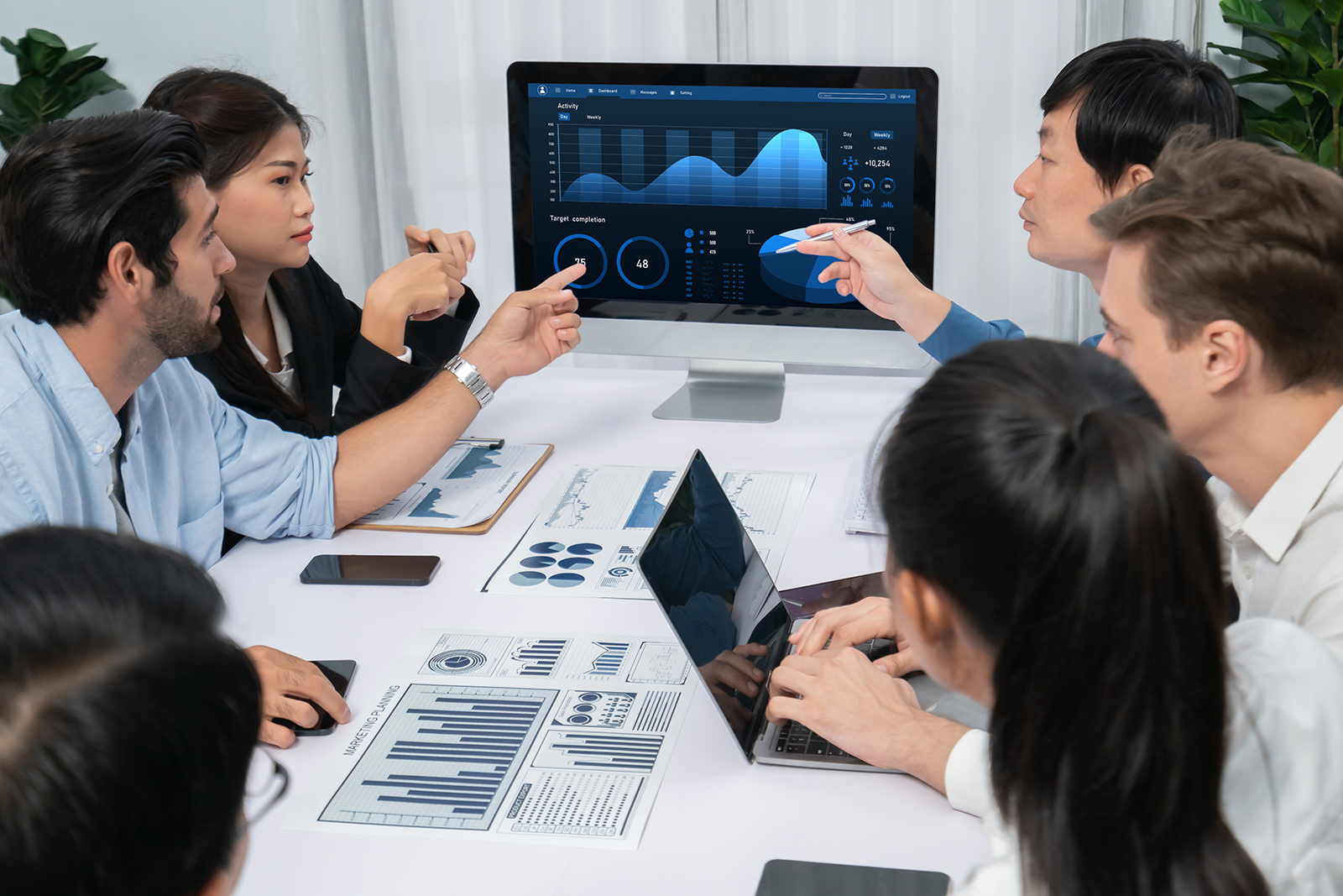 Equipe de negócios reunida analisando um painel de dados e gráficos de conversão