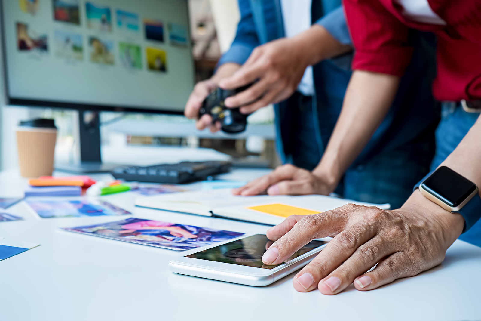 Equipe de marketing organizando conteúdo e planejando campanhas em uma mesa com celular, fotos e anotações