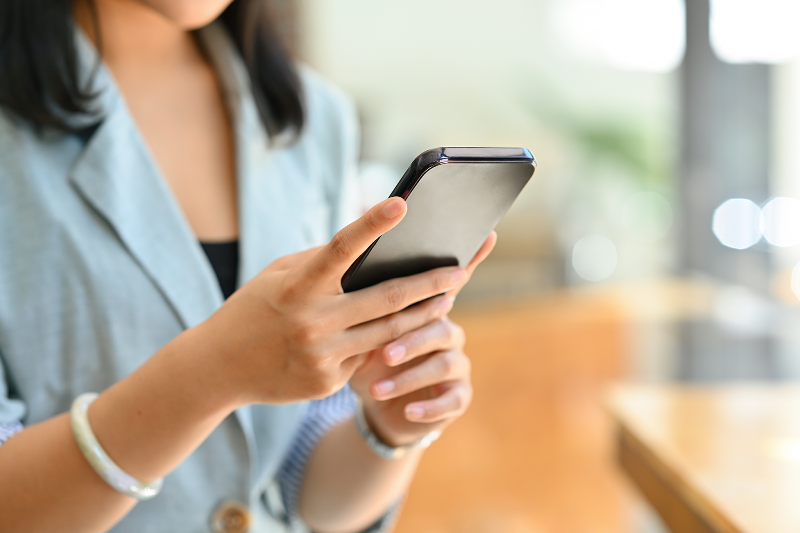 Mulher digitando mensagem de follow-up no celular em ambiente de escritório