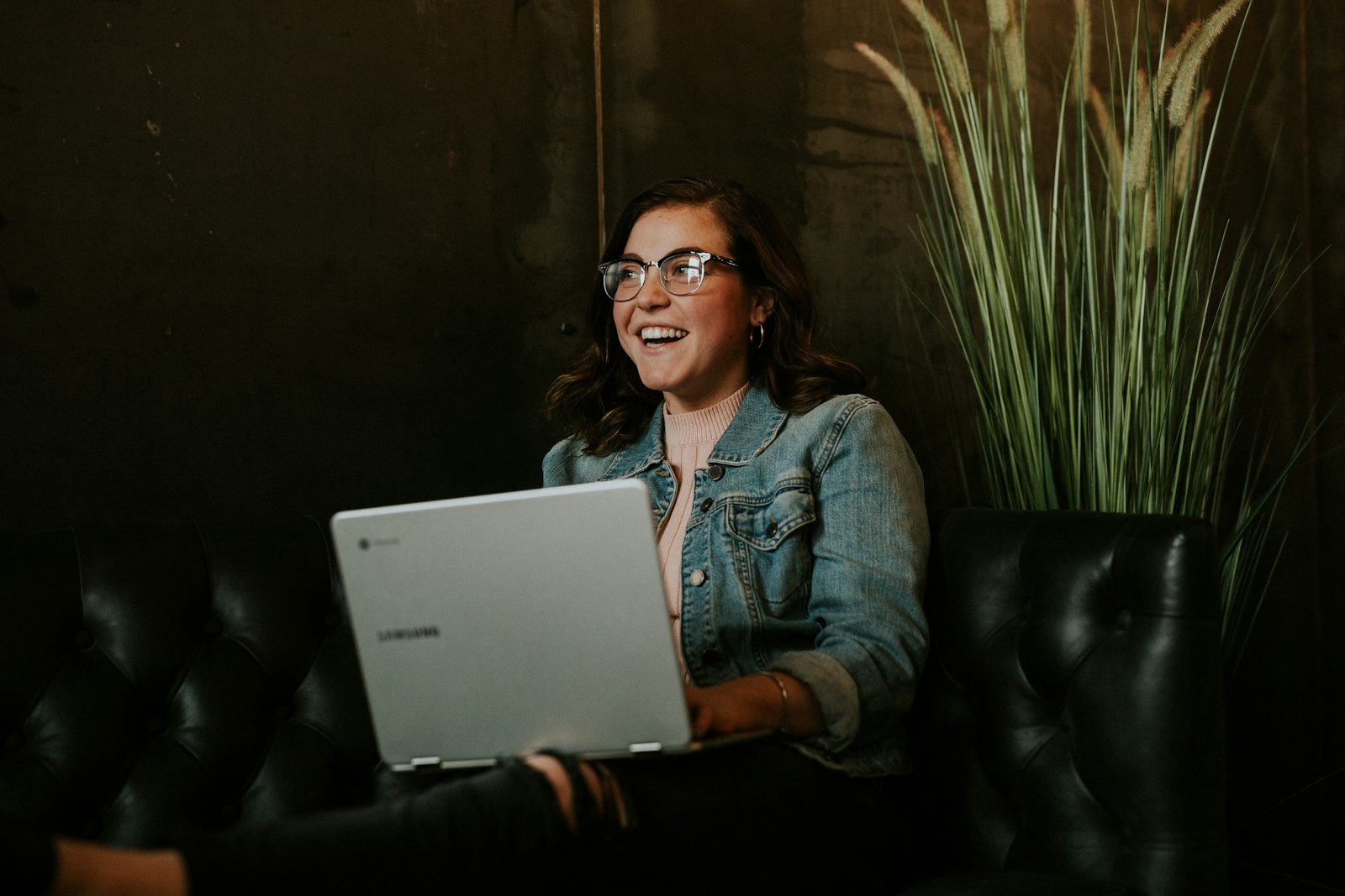Mulher usando laptop no colo em conversa de atendimento, representando o atendimento humano que complementa a IA