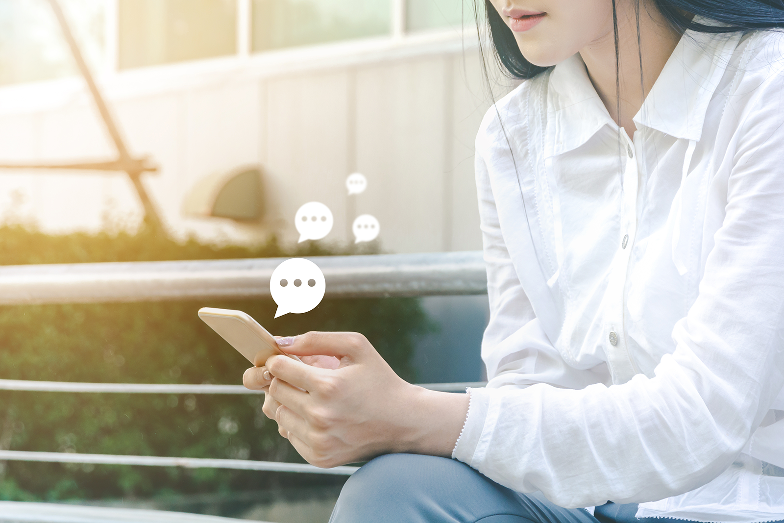 Mulher usando chatbot de IA no celular, ícones de balão de mensagem sobre o smartphone
