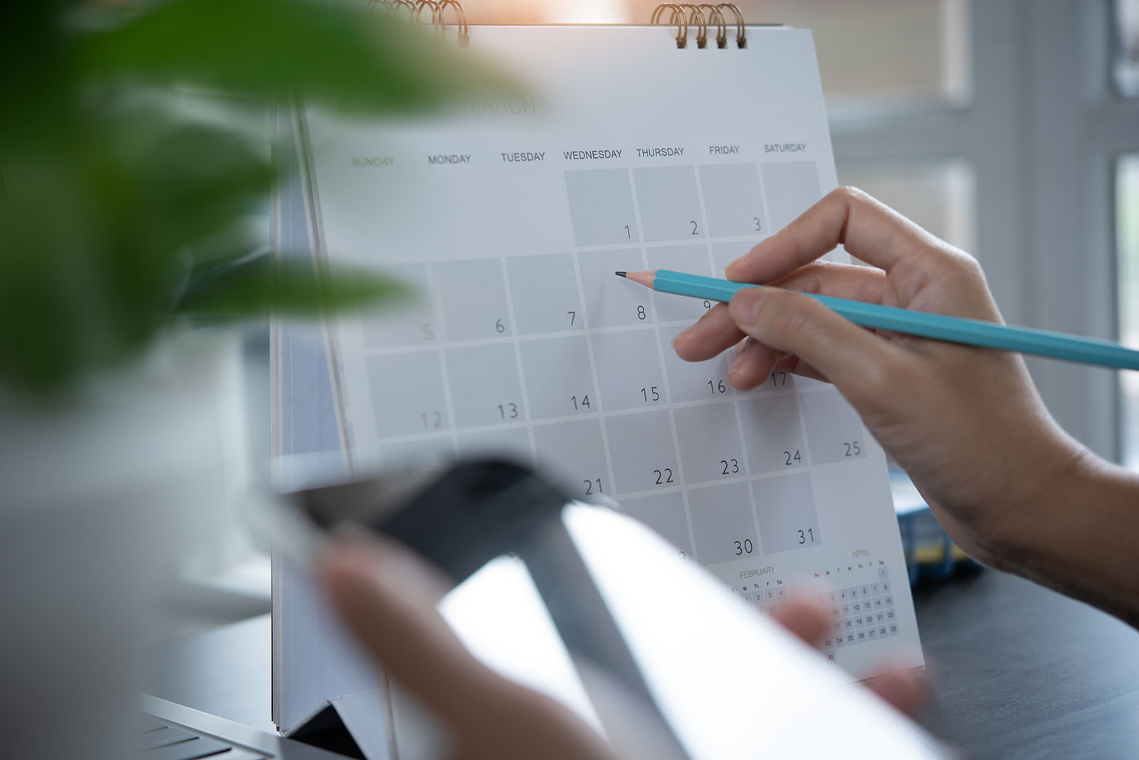Mão marcando datas em um calendário com caneta, representando a cadência de follow-up D+1 D+3 D+7