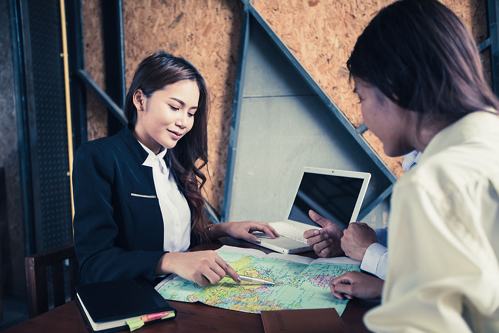 Consultora de viagens mostrando mapa e roteiro para cliente em mesa de atendimento