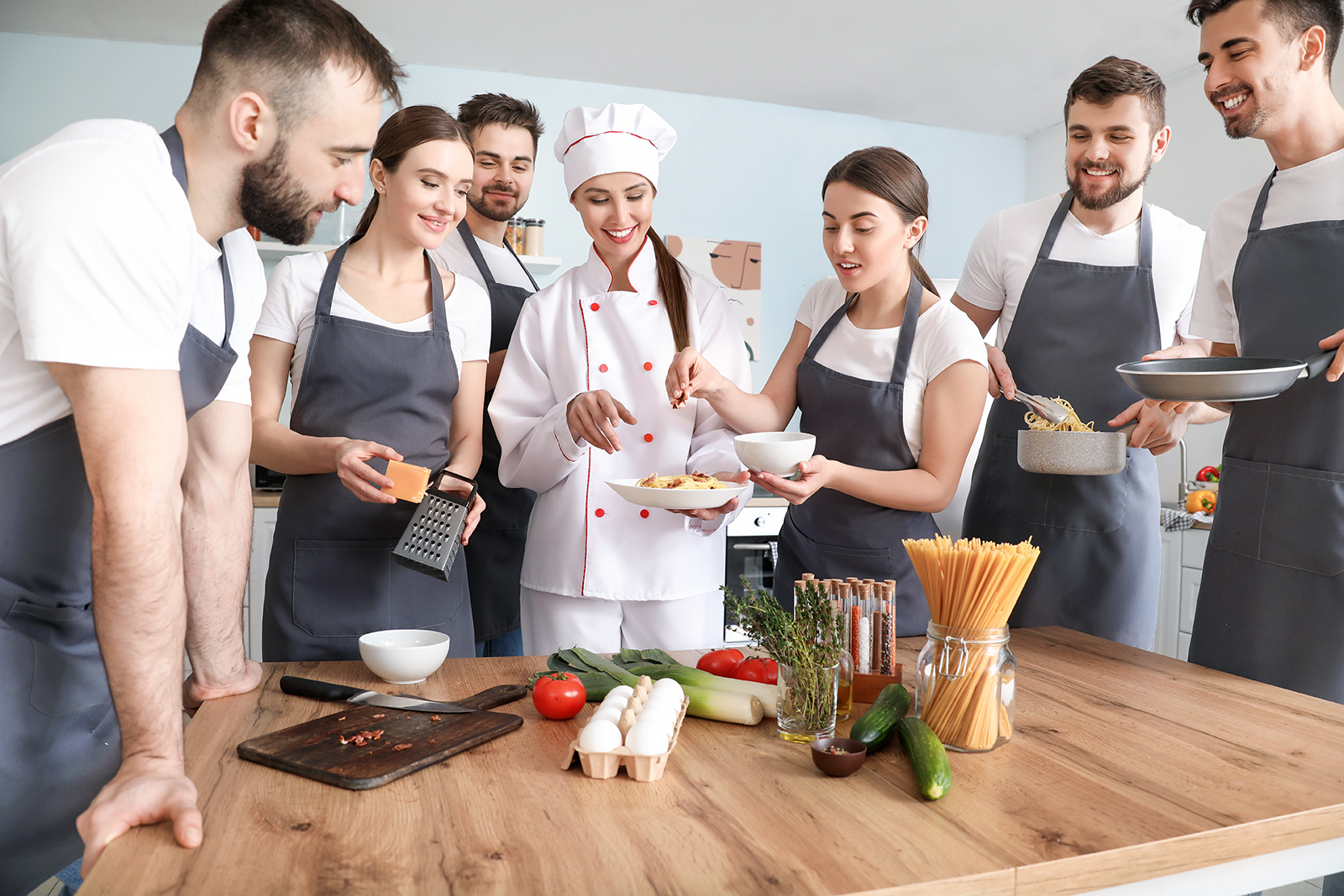 Grupo de turistas participando de aula de culinária com chef em cozinha