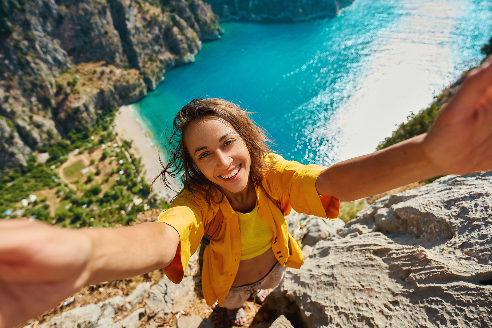 Mulher sorridente tira selfie em mirante durante viagem, compartilhando memória para redes sociais