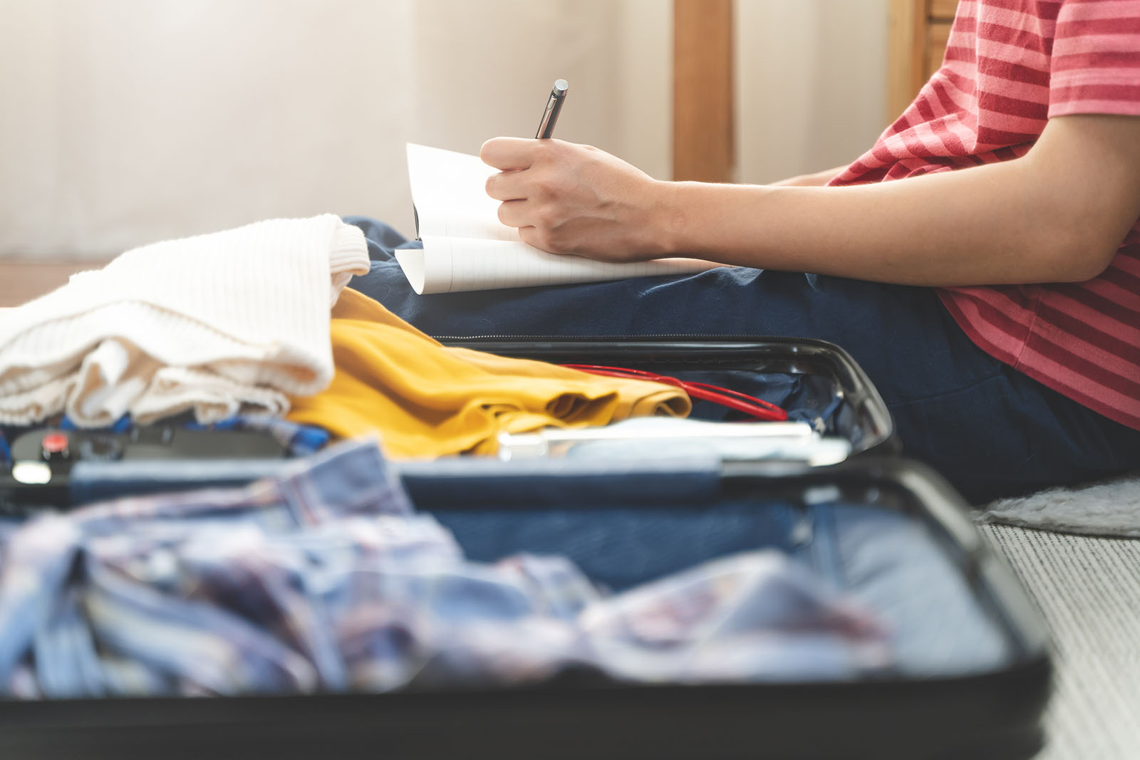 Pessoa organizando roupas e documentos dentro da mala antes da viagem