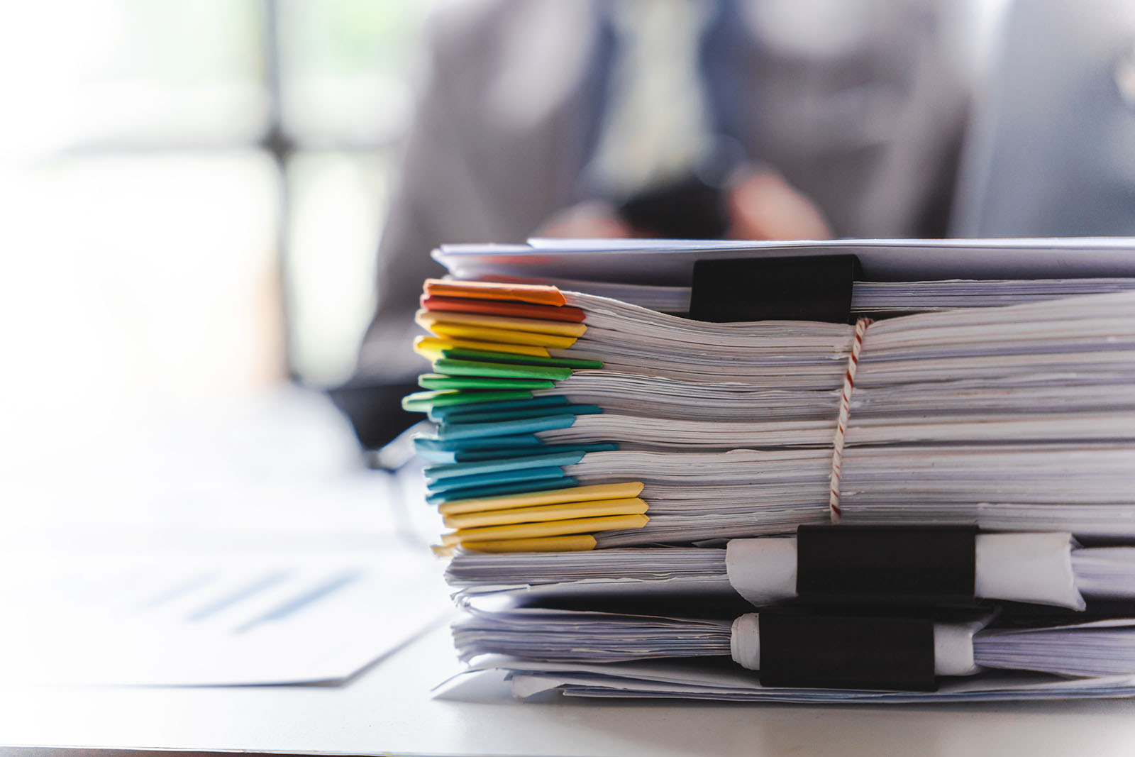 Pilha de pastas e documentos de papel empilhados em mesa de escritório, representando controle manual de leads