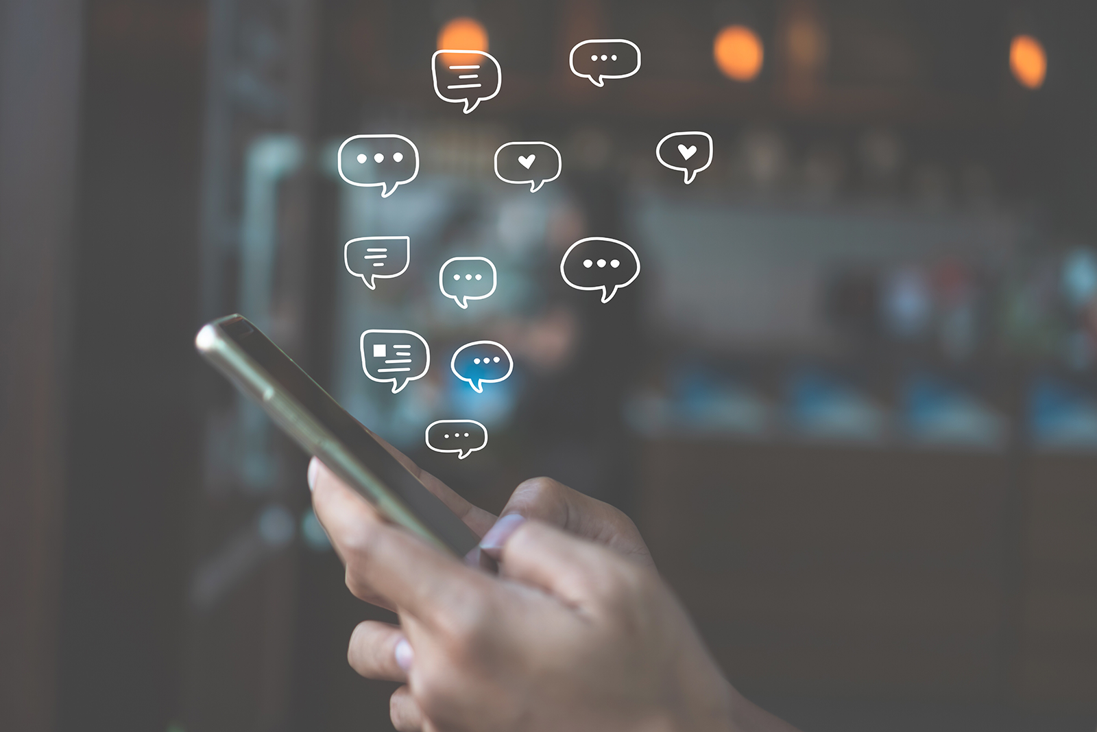 Mão segurando smartphone com ícones de chat e conversa automática de WhatsApp